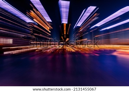 Night city street abstract background. Urban illumination of modern buildings. Futuristic effect of light trails from camera zooming motion.