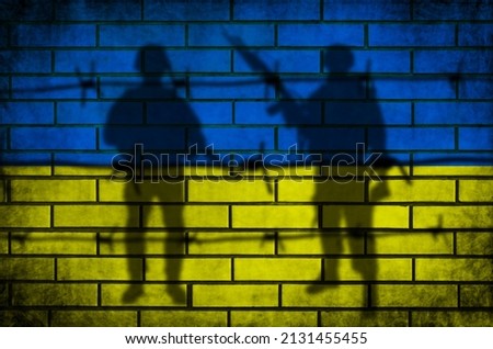 Ukraine flag and military background. Barbed fence and armed men silhouette. Conflict and war concept. Grunge texture on brick wall photo