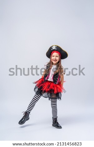 Portrait of a naughty little girl in a pirate costume, standing on a black background, A girl is preparing for the Halloween holiday. Standing tall in the studio