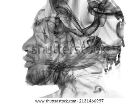 A black and white portrait of a man dissolving into smoke in a double exposure technique.