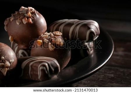Chocolates on a dark plate in a black background, concep of sweet dessert food macro photography