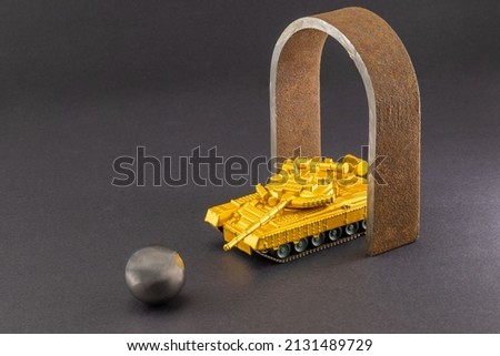 a toy tank stands in the gate in the form of a defender, aimed at a metal ball. background picture.