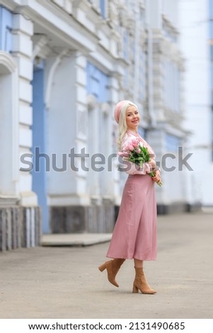 Girl holds bouquet of flowers and inhales their fragrance. Pretty girl takes lovely tulips with joy and smile. Portrait of surprised woman smelling flowers on the street
Girl holds bouquet of flowers 