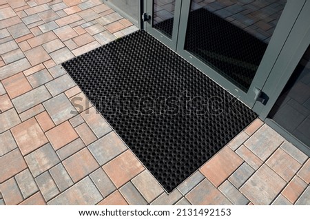 industrial mat cleaning zones at the entrance to the building. A black plastic-metal mat in the shape of an arch or half-circle lies on the limestone mosaic tiles Royalty-Free Stock Photo #2131492153