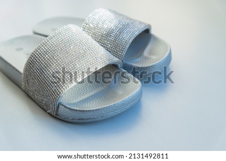 Close-up girl's or woman's ruber glamour fashion slippers standing on white background. silver flip-flop sliders. Vacation and travel concept. Copyspace
