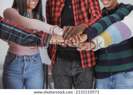Young multiracial students stacking hands inside school class room