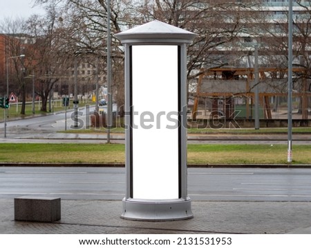 Advertising column in the city. Blank mockup for testing ad designs on the pillar next to the street. Billboard template with a white rectangle in a city. Copy space in an urban area for marketing.