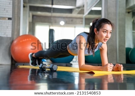 Healthy Asian athlete woman in sportswear do plank workout exercise body weight lifting at fitness gym. Strong female body building muscle weight training at sport club. Health care motivation concept Royalty-Free Stock Photo #2131540853