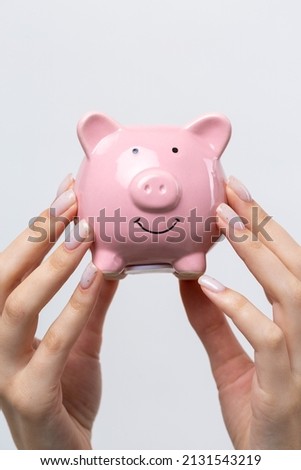3d pink piggy bank in the beautiful hands of a girl.
Close-up photo on a white background.