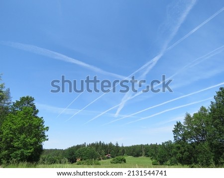White letter A in the blue sky and nature in the background. The lines from the planes in the blue sky form the first character of the alphabet.  