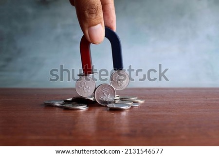 Hand holding magnet and attract coins. Business, investment and financial concept. Royalty-Free Stock Photo #2131546577