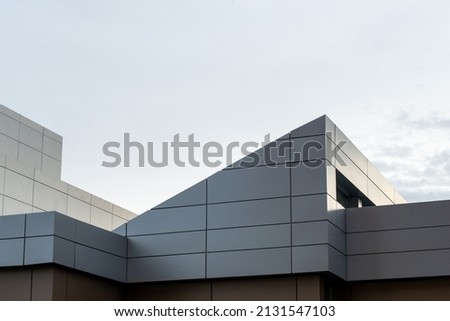 The exterior wall of a contemporary commercial style building with aluminum metal composite panels and glass windows. The futuristic building has engineered diagonal cladding steel frame panels. Royalty-Free Stock Photo #2131547103