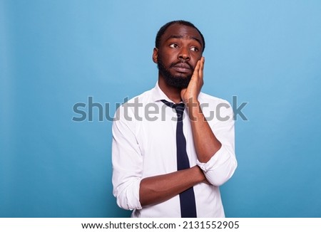Portrait of businessman having deep thoughts holding palm of hand to his face looking lost. Office employee in white shirt daydreaming thinking about professional problems at work. Royalty-Free Stock Photo #2131552905