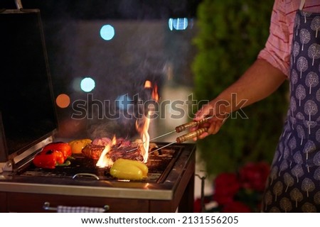 a man is grilling the food on bbq on the patio at summer evening Royalty-Free Stock Photo #2131556205