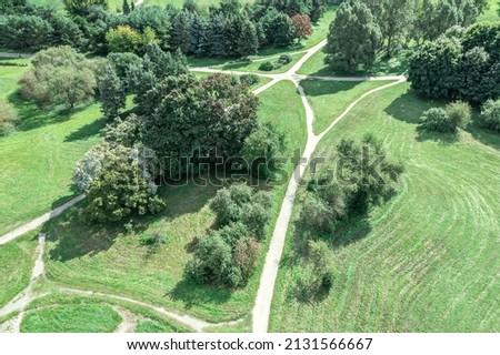 city park landscape with green trees, lawn and walking paths during summer sunny day. aerial view.