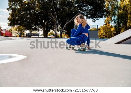 A Cheerful Caucasian woman with blonde hair skating in urban setting