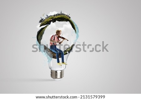 Man plays on violin sitting on light bulb
