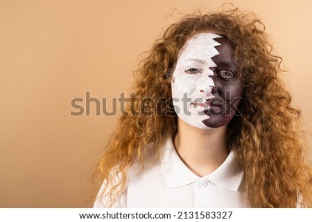 Photo of calm positive attractive lady with her hairstyle redhead curly and painted face in Qatar flag standing isolated on bright yellow background.