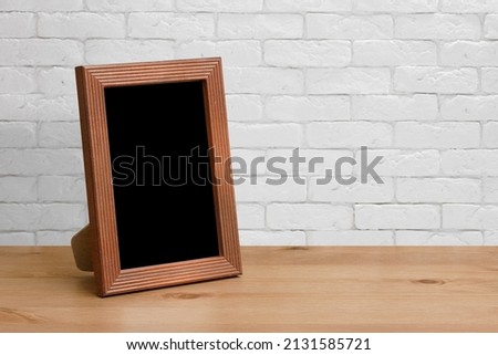 old photo frame on the wooden table, white brick wall