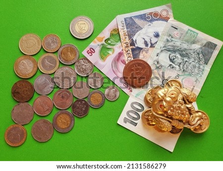 Green background with copy space with metal coins, paper bills of different countries with golden money toad.