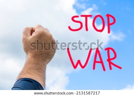 A man's hand is raised in a fist. a symbol of the struggle for peace and against war. text. the actual concept of anti-war support.