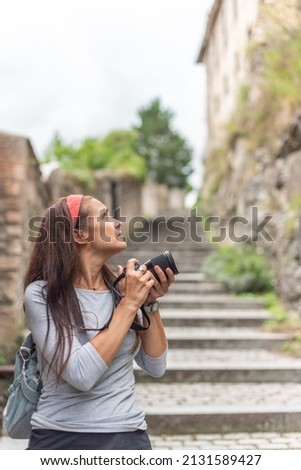 Pensive woman taking photo of old town