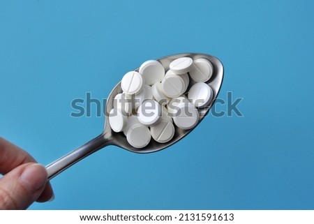 A lot of pills in a spoon. A symbol of uncontrolled self-medication with pills Royalty-Free Stock Photo #2131591613