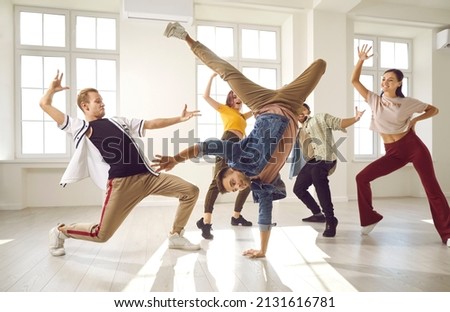 Hip hop dancers in dance studios. Young people who practice modern dance styles have fun and dance together in spacious bright hall. Cheerful, talented and active dancers in casual clothes.