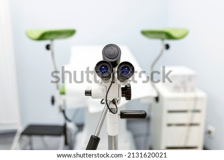 Focus on optical instrument for colposcopy in gynecological cabinet. Empty gynecology office with modern colposcope and medical tools. Concept of gynecology, obstetrics and medical equipment. Royalty-Free Stock Photo #2131620021