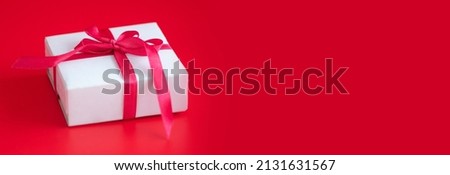 gift box with red ribbon on a red background, banner with space for text. High quality photo