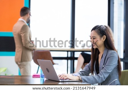 Asian female employee using computer laptop working in co-working space at the office. browsing internet,  work online, financial business