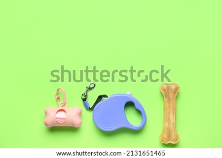 Pet waste bags, leash and chew bone on green background