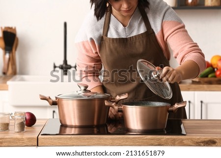 Woman cooking in copper pot at home Royalty-Free Stock Photo #2131651879