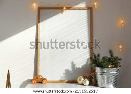 Christmas decor and blank frame on table in room
