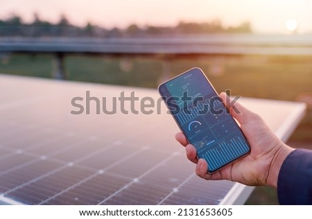 Man hand holding the telephone for monitoring performance in solar power plant(solar cell). Alternative energy to conserve the world's energy, Photovoltaic module idea for clean energy production. Royalty-Free Stock Photo #2131653605