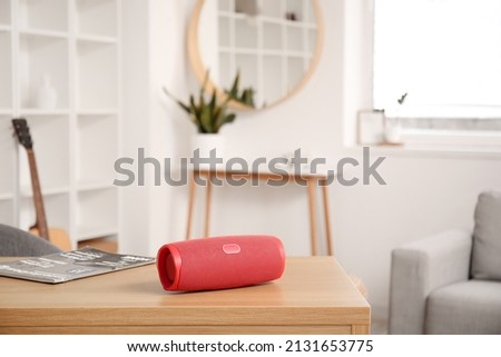 Wireless portable speaker on wooden table in light room Royalty-Free Stock Photo #2131653775