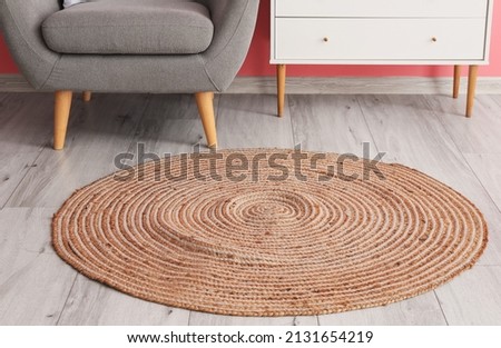 Stylish wicker carpet on light wooden floor in room interior Royalty-Free Stock Photo #2131654219