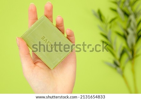 natural soap. olive branch. Hand holds a homemade soap with the inscription "olive". Sustainable hygiene products. woman holding handcrafted green soap on green surface. homemade natural olive soap
