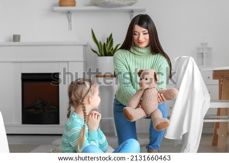 Happy mother giving toy to her little daughter at home