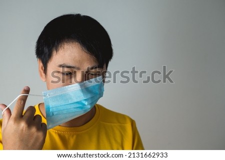 The man twists medical mask’s straps. This method helps to improve the fit and filtration of mask. Protection global pandemic of coronavirus. Other name of this disease calls COVID-19.  