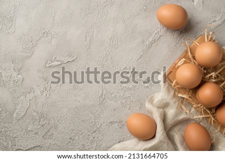 Top view photo of brown easter eggs cloth straw and wooden egg holder on isolated grey concrete background with copyspace