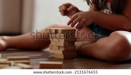 Child playing with wooden building blocks. Kid trial and error play