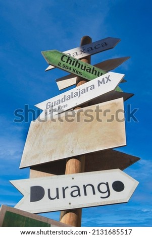 sign post with multiple arrows pointing to different locations in Mexico and a customizable blank banner