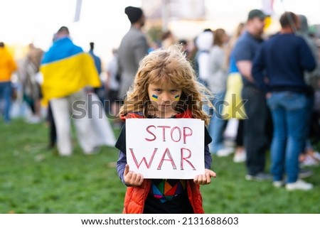 Young kid holding a poster with Stop war message, activism and human rights movement, outdoor lifestyle. Child carries a sign Stop war. Russian geopolitics and crisis in Ukraine.