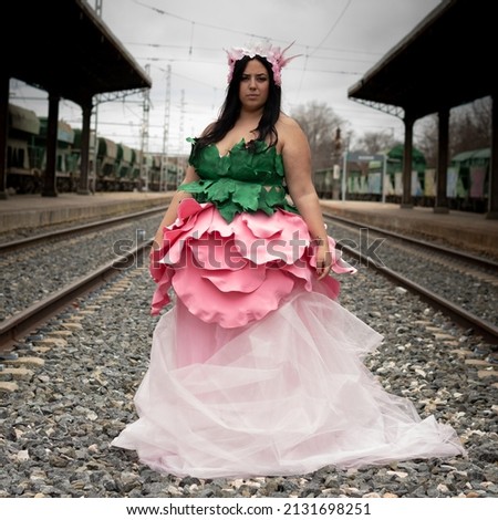 Thick woman dressed as a flower on an abandoned train track.