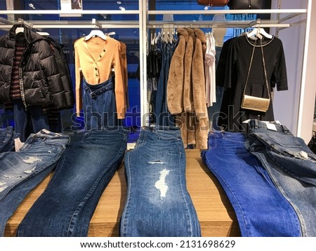 Shopping and clothing store concepts. various blue Jeans and jacket jeans and  on a hanging rack in the clothes store with shoes 

