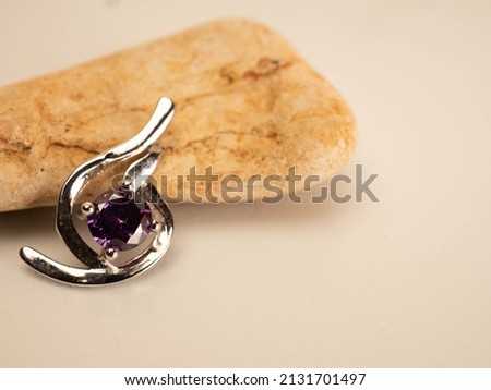 Close up shot of white gold pendat with shiny purple stone