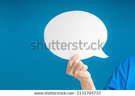 A speech bubble concept. Hand holding of a blank white speech bubble on a blue background. Space for text Royalty-Free Stock Photo #2131704733