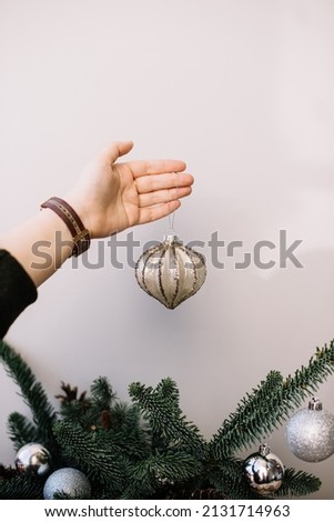 Woman's hand holding beautiful hand made Christmas bauble on the grey background, vertical photo