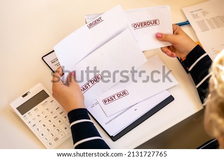 An accountant looks at debt envelopes as a concept of growing delinquent debts, rising prices, and declining incomes. Royalty-Free Stock Photo #2131727765
